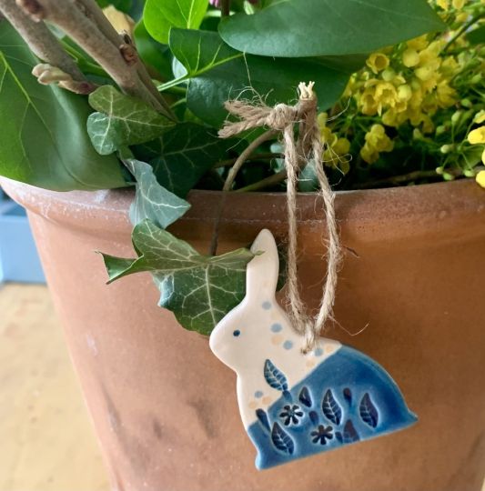 kerámia kék mázas húsvéti nyúl díz lóg egy cserép virágon