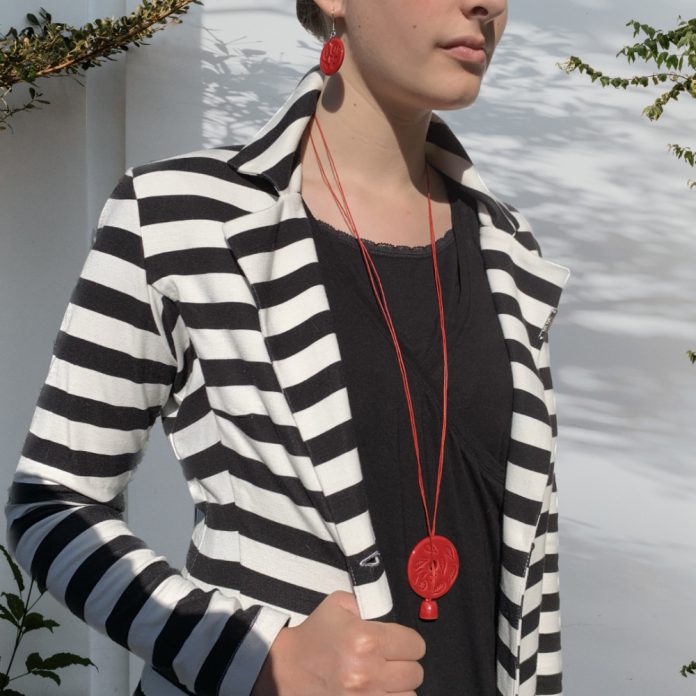 piros nyakláncot viselő nő csíkos zakóban