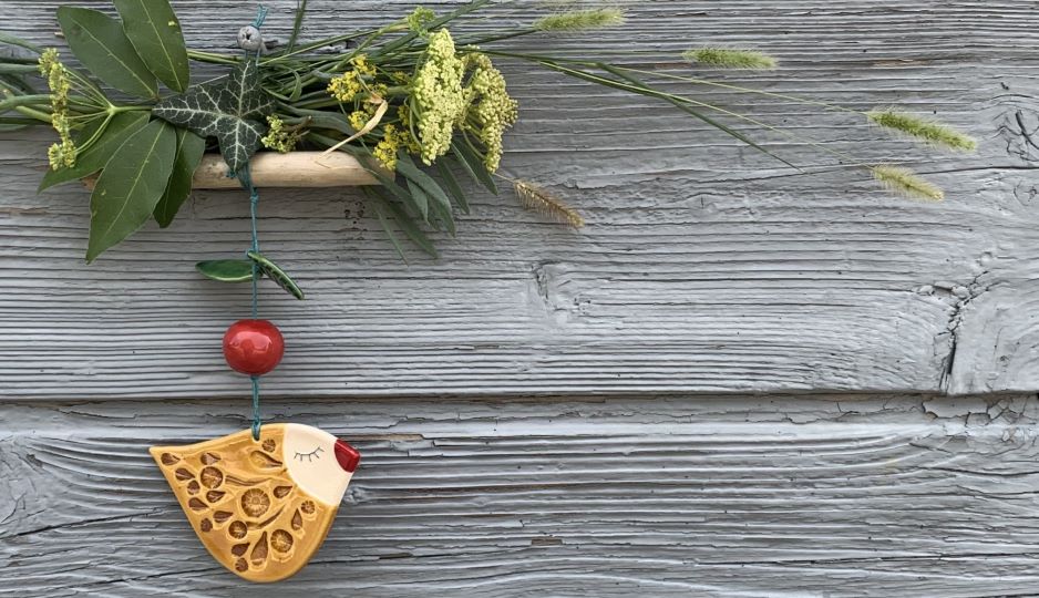 sárga kerámia madaras ajtódísz, fa háttér előtt