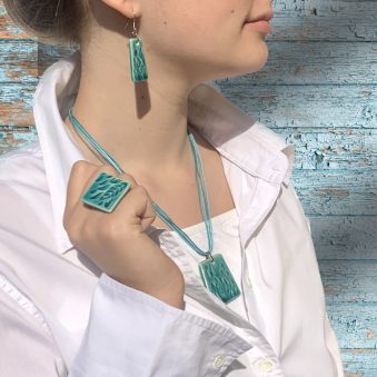 Nő türkiz kerámia ékszer szettben, fehér blúzban