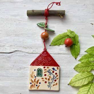 Piros, cseréptetős házikó, őszi színekben pompázó kerttel és egy kék madárkával